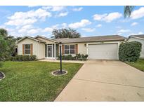 Beige one-story house with a two-car garage and landscaping at 2788 Privada Dr, The Villages, FL 32162