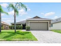 Tan single story house with a two car garage and lush landscaping at 806 Knightsbridge Cir, Davenport, FL 33896