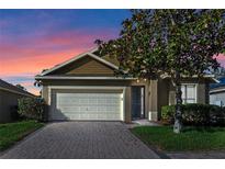 House exterior featuring a two-car garage and well-manicured landscaping at 437 Bridgeford Crossing Blvd, Davenport, FL 33837