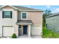 Tan two-story townhome with two-car garage and curb appeal at 1273 Yellow Finch Dr, Davenport, FL 33837