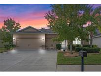 Two-story house with beige siding, three car garage, and landscaped yard at 5307 Cortland Dr, Davenport, FL 33837