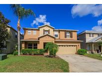 Two story house with tan exterior, landscaping, and a two-car garage at 315 Aldridge Ln, Davenport, FL 33897