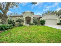 Tan house with a two-car garage and manicured lawn at 3857 Fallscrest Cir, Clermont, FL 34711