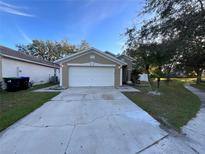 Tan house with a two-car garage and landscaping at 2416 Sapier Ct, Orlando, FL 32837