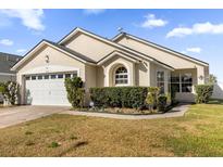 Tan house with a two-car garage and well-manicured lawn at 2660 Oneida Loop, Kissimmee, FL 34747