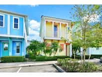 Charming yellow two-story townhome with coral accents and lush landscaping at 3013 Sea Plane Ln, Kissimmee, FL 34747