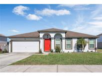 Single-story home with a white exterior, red door, and attached garage at 3618 Wellington Ln, Bartow, FL 33830