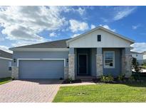 Gray house with white accents, stone facade, and a two-car garage at 6817 Serpent Hawk Lane St, Howey In The Hills, FL 34737