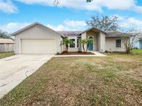 Tan one-story house with attached garage and landscaping at 5119 Timber Ridge Trl, Ocoee, FL 34761