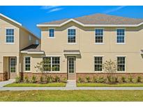 Two-story tan house with stone accents and landscaping at 141 Holly Village Dr, Davenport, FL 33837