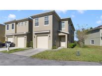 Tan two-story townhome with a two-car garage and a small front yard at 470 Lake Shore Pkwy, Davenport, FL 33896