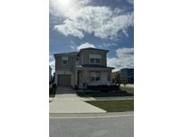Two-story house with light brown siding, shutters, and a paved driveway at 8918 Tropical Haven Ct, Kissimmee, FL 34747