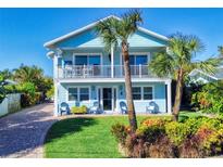 Two-story light blue house with balcony, landscaping, and a paved driveway at 110 Surf St, New Smyrna Beach, FL 32169