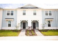 Two-story light blue townhome with white accents and a walkway at 1290 Shoreside St, Clermont, FL 34714