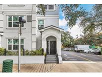 Exterior view of a light gray building with a black door, steps, and landscaping at 204 E South St # 1055, Orlando, FL 32801
