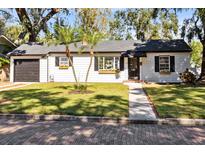 Charming white house with black accents, landscaped lawn, and brick driveway at 1403 E Pine St, Orlando, FL 32801