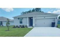 Single-story house with attached garage, landscaping, and driveway at 310 Gardenia Ct, Poinciana, FL 34759