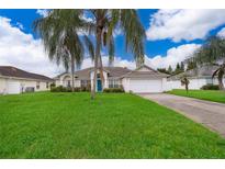 Single-story house with a green lawn, driveway, and palm trees at 577 Sunridge Woods Blvd, Davenport, FL 33837