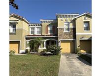 Two-story townhome with a yellow garage door and landscaping at 3006 Seaview Castle Dr, Kissimmee, FL 34746