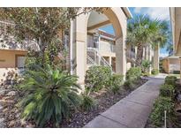 Well-maintained condo building with landscaped grounds and walkway at 2711 Emerald Lake Ct, Kissimmee, FL 34744