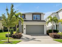 Two-story modern home with gray siding, paver driveway, and landscaping at 836 Desert Mountain Ct, Reunion, FL 34747