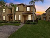 Two-story townhome with brick paver driveway and landscaped lawn at 408 Miramar Avenue, Davenport, FL 33897