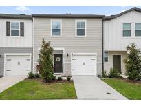 Two-story townhome with gray siding, white accents, and a two-car garage at 397 Madison Dr, Davenport, FL 33837
