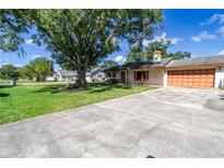 Ranch home with a large front yard, mature trees, and a long driveway at 1741 Kings Hwy, Kissimmee, FL 34744