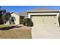 Tan house with a two-car garage and well-manicured lawn at 148 Country Walk Cir, Davenport, FL 33837