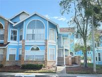 Inviting light blue exterior of a two-story townhome with stairs and landscaping at 2749 N Poinciana Blvd # 16, Kissimmee, FL 34746