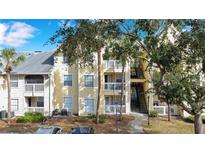 Front view of condo building, featuring a yellow exterior and lush landscaping at 1037 S Hiawassee Rd # 2815, Orlando, FL 32835