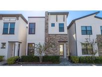 Modern three-story home with stone accents and a landscaped front yard at 172 Villa Domani Cir, Davenport, FL 33896