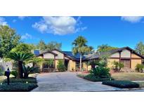 Beautiful yellow home with solar panels, lush landscaping, and a long driveway at 872 Huckleberry Ln, Winter Springs, FL 32708