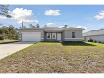 Newly constructed one-story home with gray siding, a white door, and a two-car garage at 2470 170Th Pl, Ocala, FL 34473