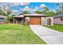 Single-story home with stone exterior, wood garage door, and landscaped lawn at 2511 Yale Ave, Sanford, FL 32773