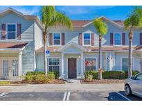 Light blue townhome with dark brown accents, landscaping, and parking at 3205 Gold Ln, Kissimmee, FL 34747