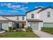 Two-story townhome with light-colored siding, attached garage, and landscaping at 1592 Wynford Cir, Tavares, FL 32778