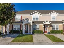 Tan two-story townhome with dark brown doors and landscaping at 2361 Silver Palm Dr, Kissimmee, FL 34747