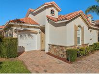 Front view of charming villa with brick driveway and landscaping at 404 Brunello Dr, Davenport, FL 33897