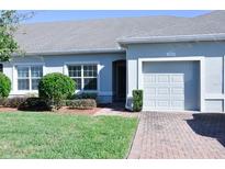 Well-maintained light blue house with a two-car garage and neatly landscaped lawn at 2825 Attwater Loop, Winter Haven, FL 33884