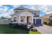 Two-story house with stone accents, a three-car garage, and well-manicured landscaping at 4381 Davos Dr, Clermont, FL 34711
