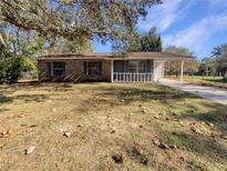 Brick ranch home with carport, mature landscaping, and a spacious yard at 12129 Se 95Th Ter, Belleview, FL 34420