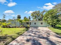 Light blue house with a brick driveway, landscaping, and lush green lawn at 2410 Sanford Ave, Sanford, FL 32771
