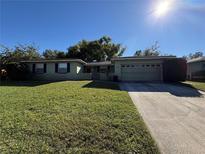 Ranch style home with a well-manicured lawn and attached garage at 451 Lowndes Sq, Casselberry, FL 32707