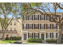 Tan three-story townhome with black shutters and lush landscaping at 1054 Waterside Dr, Celebration, FL 34747