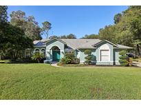 Single-story house with teal exterior, landscaping, and a teal front door at 1468 Deer Lake Cir, Apopka, FL 32712