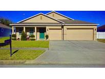 Tan house with green door, two-car garage, and well-manicured lawn at 236 Barrington Dr, Haines City, FL 33844