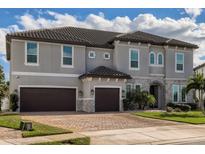Two-story house with gray exterior, brown garage doors, and landscaping at 8192 Ludington Cir, Orlando, FL 32836