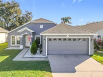 Gray house with a two-car garage and landscaped lawn at 1005 Cherry Valley Way, Orlando, FL 32828