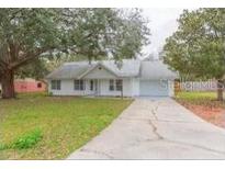 White single story home with a green lawn and driveway at 4 Cedar Trace Way, Ocala, FL 34472